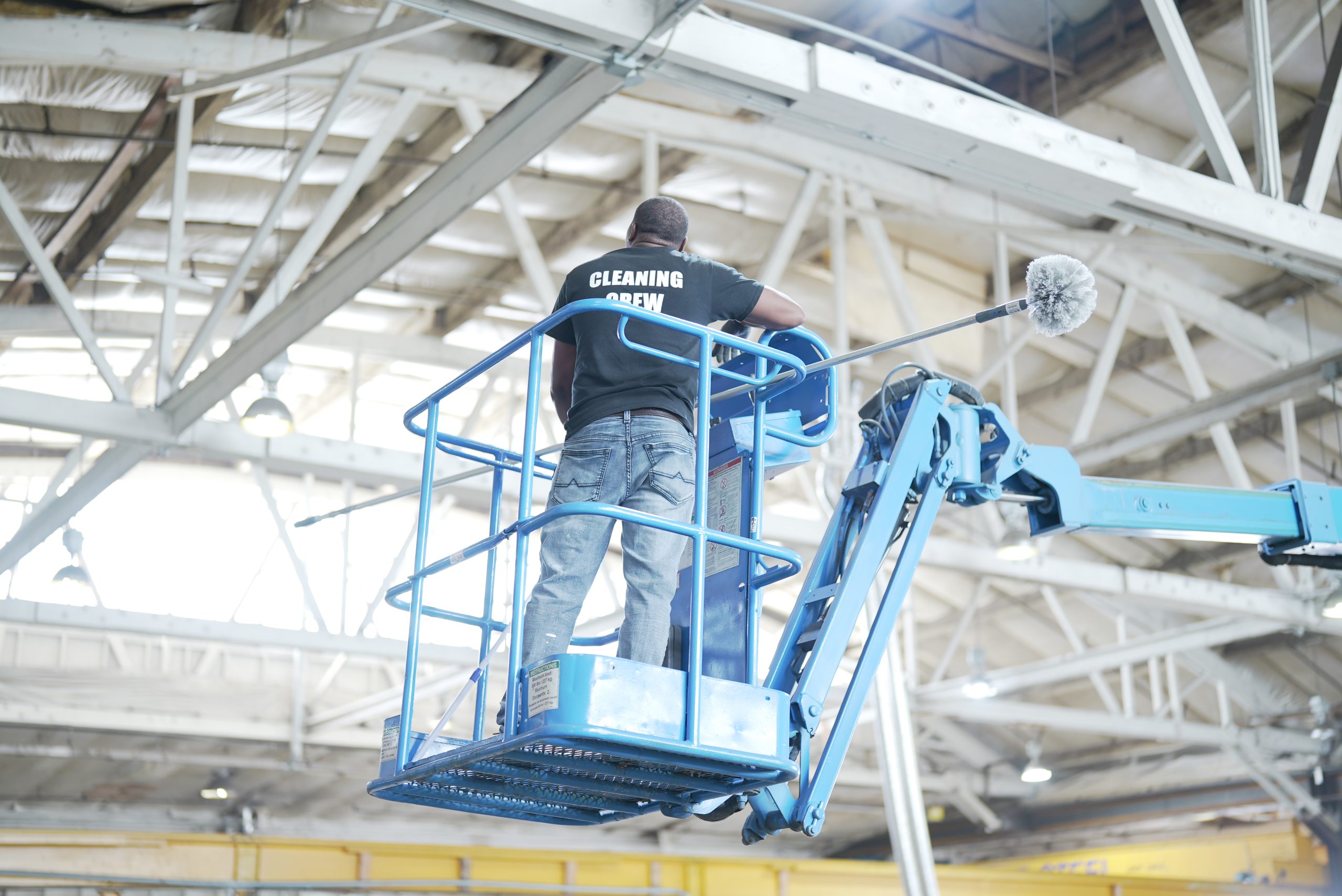 Technician on a lift cleaning warehouse rafters Technician on a lift cleaning warehouse rafters
